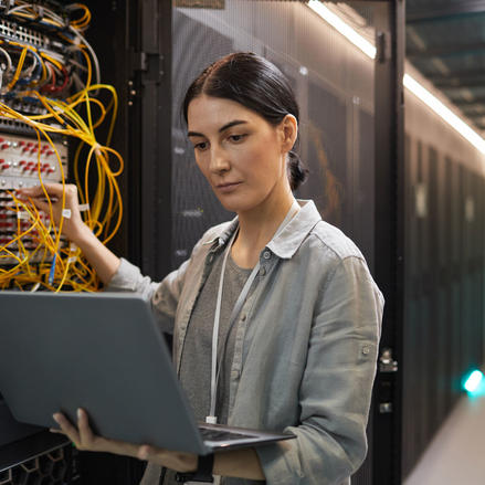 Technikerin überprüft ein Netzwerk mit ihrem Laptop im Serverraum